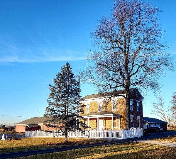 White vinyl picket fence around a farmhouse in winter